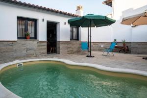 basen z parasolem obok domu w obiekcie Apartamentos Rurales Helechosa, Las Tres Peñas w mieście Helechosa