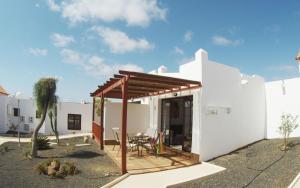 a white house with a wooden roof and a patio at Castillo Sol Bungalow in Caleta De Fuste