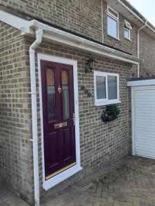 a purple door on the side of a brick house at Home from home, single room with virgin channels, Wifi & free parking in Poole