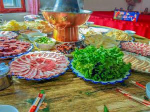 een tafel met veel verschillende soorten vlees en groenten bij Rime Island Manzhaosongju Inn in Jilin