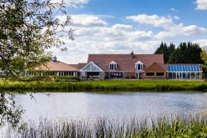 ein Haus mit einem Teich davor in der Unterkunft Kingfisher Hotel, Golf and Country Club in Milton Keynes