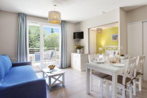 a living room with a table and a blue couch at Résidence Odalys Les Océanides in La Londe-les-Maures