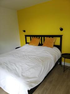 a large white bed in a room with a yellow wall at DURBUY-COSY Appartement 2 in Durbuy