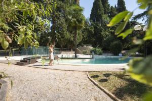 a woman is walking by a swimming pool at Hotel Villa Quiete in Montecassiano