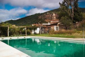 a swimming pool in front of a house with a mountain at Posada San Marcos in Alájar