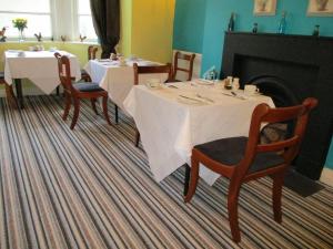a dining room with two tables and chairs and a fireplace at Cranborne Guest Accommodation Exclusively for Adults in Torquay