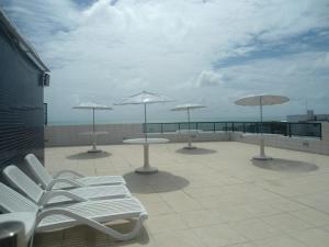 a patio with white chairs and umbrellas on a roof at Atlântico Tambaú Home Service in João Pessoa