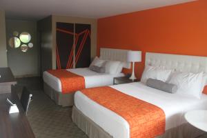 Howard Johnson Inn by Wyndham Kingston في كينغستون: غرفة فندق بسريرين بجدران برتقالية