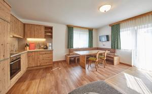 kuchnia z drewnianymi szafkami, stołem i krzesłami w obiekcie Appartements Christine w mieście Maishofen