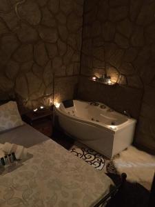 a bathroom with a tub and a bed with lights at To Konaki in Synikia Mesi Trikalon