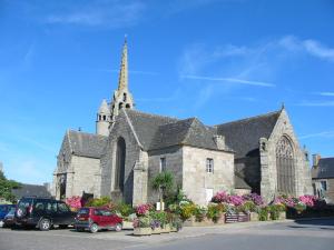 a church with cars parked in a parking lot at En Bretagne, villa de 2 à 8 pers , meublé de tourisme 3 étoiles nichée dans un écrin de verdure à 2500m de la plage in Ploumilliau