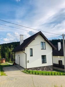 Biały dom z czarnym dachem w obiekcie Belvedere-Karpaty w mieście Schodnica