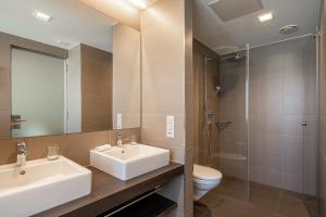 a bathroom with a sink and a toilet and a mirror at Hotel Artos Interlaken in Interlaken +84 photos