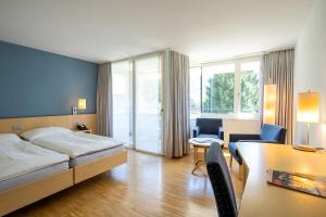 ein Hotelzimmer mit einem Bett, einem Tisch und Stühlen in der Unterkunft Hotel Artos Interlaken in Interlaken