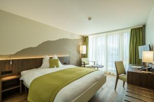 a bedroom with a large bed with a green blanket at Hotel Artos Interlaken in Interlaken