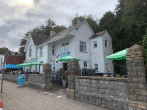 um edifício branco com guarda-chuvas verdes à frente em Sids restaurant and bar with rooms em Cardiff