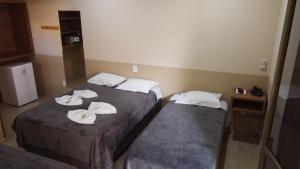 two beds in a hotel room with towels on them at Pousada Kaluanã in Olímpia