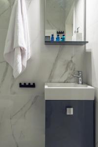 a white bathroom with a sink and a mirror at The Averof (Kalimarmaro) City Center Apartment in Athens