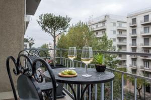 una mesa con 2 copas de vino en el balcón en The Averof (Kalimarmaro) City Center Apartment, en Atenas