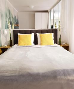 1 dormitorio con 1 cama grande con almohadas amarillas en Old Motława Mirror Apartment, en Gdansk