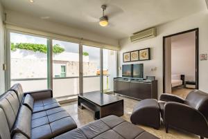 a living room with a couch and a television at Duplex w Rooftop Plunge Pool – Walk to Beach in Playa del Carmen