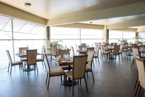 a dining room with tables and chairs and windows at Malaika Beach Resort in Mwanza