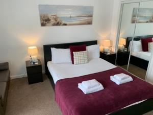 a bedroom with a large bed with two towels on it at Caledonian Apartment in Perth