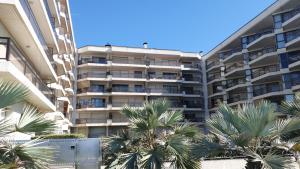 un immeuble avec des palmiers en face de celui-ci dans l'établissement Apartamento en primera linea de mar - Sant Antoni de Calonge, à Calonge