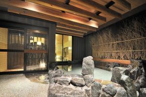 a lobby with rocks and a chair and ceiling at Dormy Inn Obihiro in Obihiro