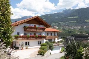una casa con fiori sui balconi con montagne sullo sfondo di Garni Pircher a Tirolo