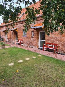 ein Backsteingebäude mit zwei Bänken in einem Hof in der Unterkunft Remise Kairies in Wustrow