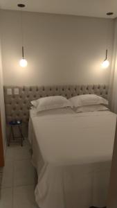 a bedroom with a large white bed with two lights at 410 Everest Flat Service in Caldas Novas