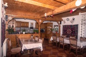a dining room with tables and chairs and a kitchen at Pensiunea Bontos in Budeşti