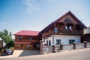 een groot houten huis met een balkon aan een straat bij Pensiunea Bontos in Budeşti
