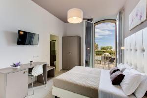 a bedroom with a bed and a desk and a balcony at Hotel Villa Augustea in Rimini