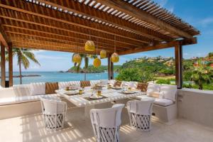 an outdoor dining area with a table and chairs and the ocean at Private Villas in Careyes in Careyes