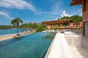 an infinity pool at a resort with a view of the ocean at Private Villas in Careyes in Careyes