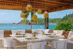 a table with white chairs and a view of the ocean at Private Villas in Careyes in Careyes