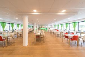 ein Esszimmer mit Tischen, Stühlen und Fenstern in der Unterkunft Bildungs- und Tagungshaus Haus Neuland in Bielefeld