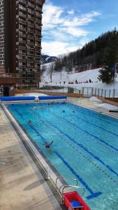 a large swimming pool with people in the water at travelski home classic - Résidence Soyouz in Le Corbier