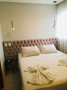 une chambre avec un grand lit avec des draps blancs dans l'établissement 410 Everest Flat Service, à Caldas Novas
