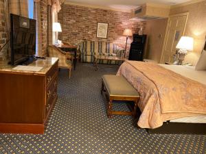 a hotel room with a bed, chair, desk and television at Place D'Armes Hotel in New Orleans
