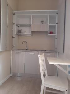 eine weiße Küche mit einem weißen Stuhl und einem Waschbecken in der Unterkunft Affittacamere Stazione Empoli in Empoli