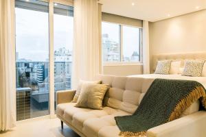 a bedroom with a couch and a large window at Pool | Food hall | 450m from the mall #CA03 in Florianópolis