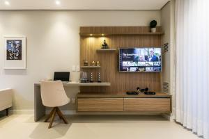 a room with a desk and a tv on a wall at Pool | Food hall | 450m from the mall #CA03 in Florianópolis