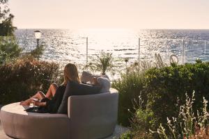 two women sitting on a couch looking at the ocean at Bellevue On The Beach Suites in Rhodes Town
