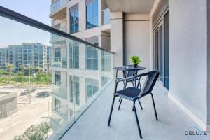 a chair on the balcony of a building at Exceptional 1BR in MAG 5, Emaar South by Deluxe Holiday Homes in Dubai