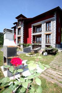 een rood-wit gebouw met een bloem ervoor bij Apartamentos Rurales La Viña in Cangas de Onís