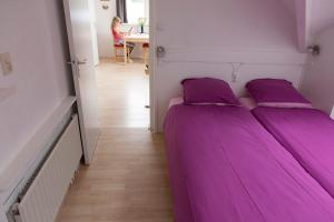 two beds in a room with purple sheets at Appartement Zuidstraat Domburg in Domburg