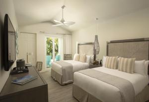 a hotel room with two beds and a table and a ceiling fan at Bungalows Key Largo - All Inclusive in Key Largo